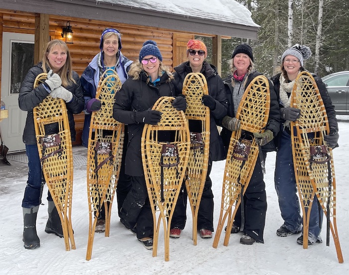 6 Small Group Women holding their snowshoes at an outdoor small group event.